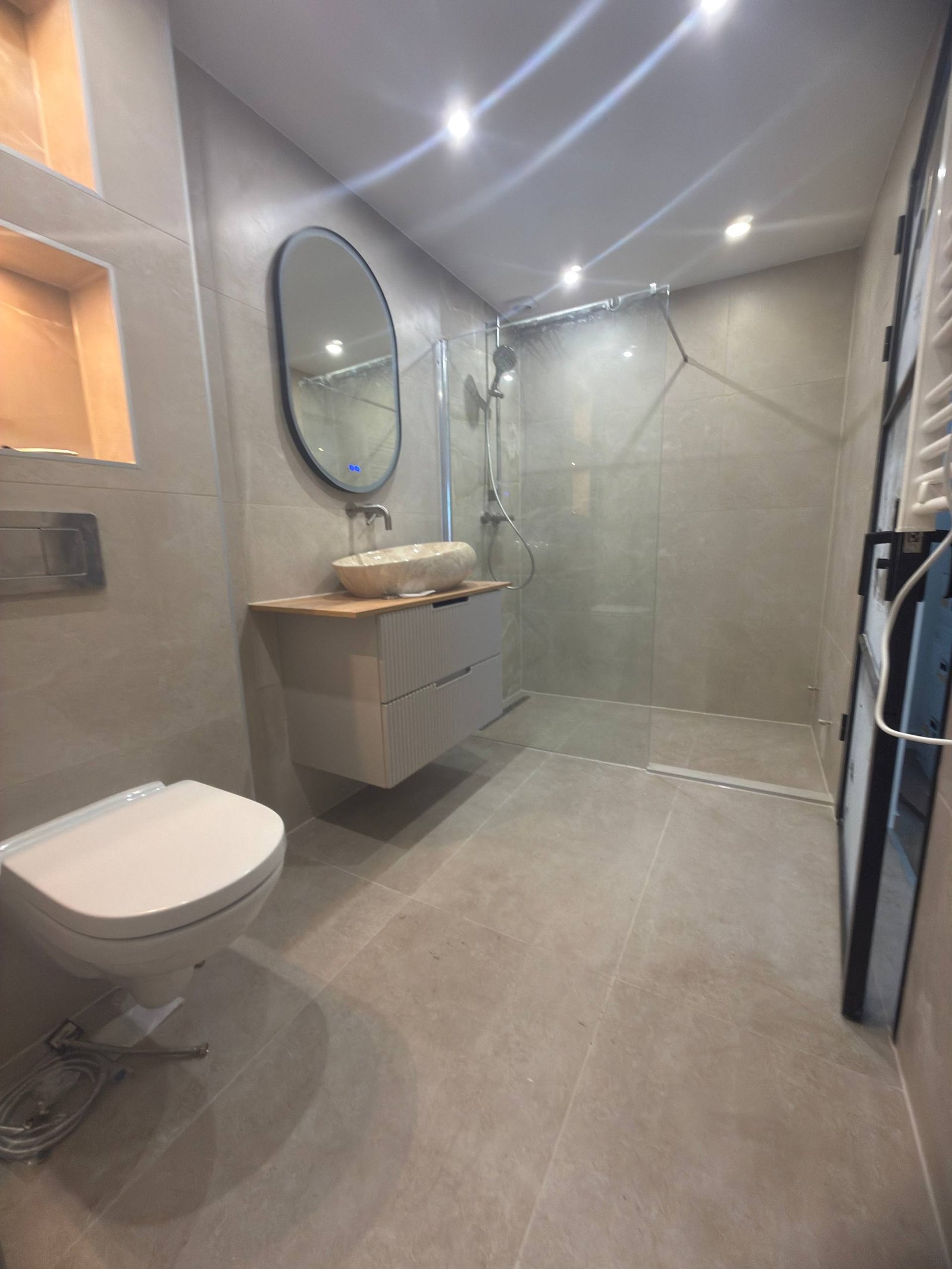 Overzicht van de gerenoveerde badkamer met toilet, wastafel en douche